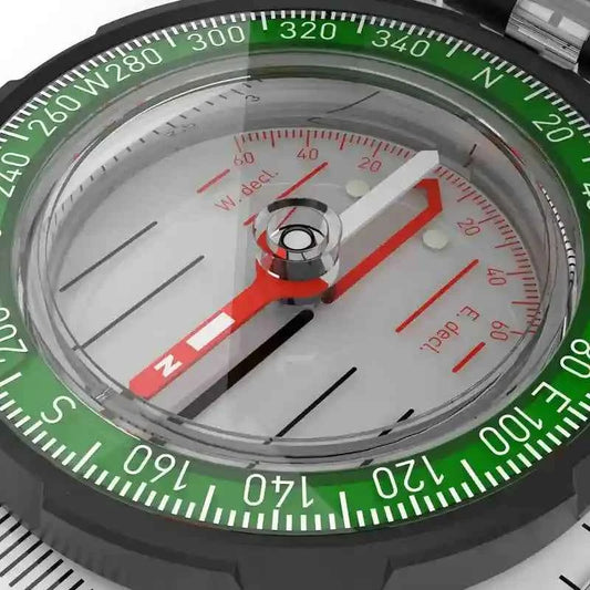 Carcasa circular de brújula con aguja roja y marcas verdes de dirección