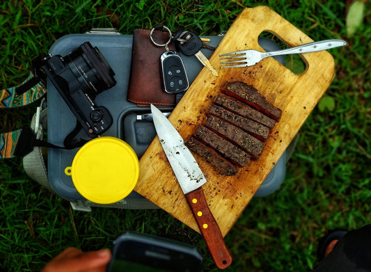 carne en rodajas sobre una tabla de cortar marrón junto a una cámara réflex digital negra