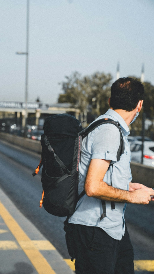 a man with a backpack is standing on the side of the road