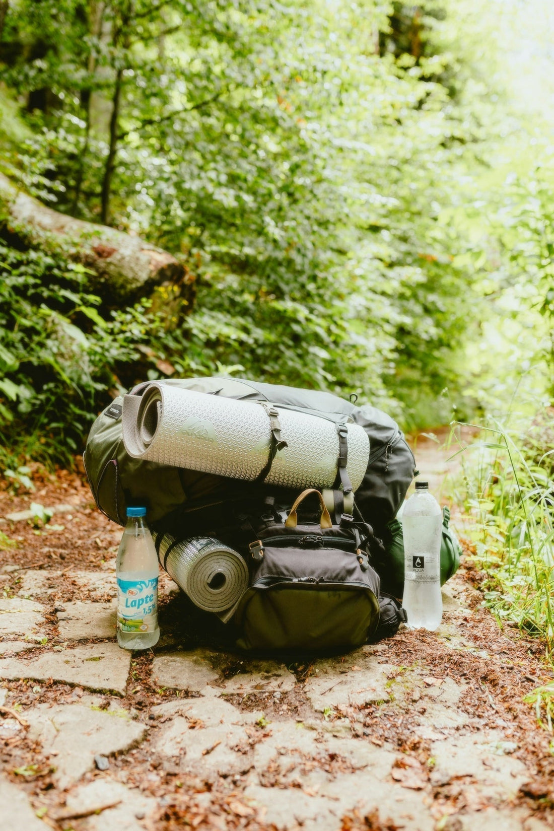 Una mochila tirada al costado de un camino de tierra.