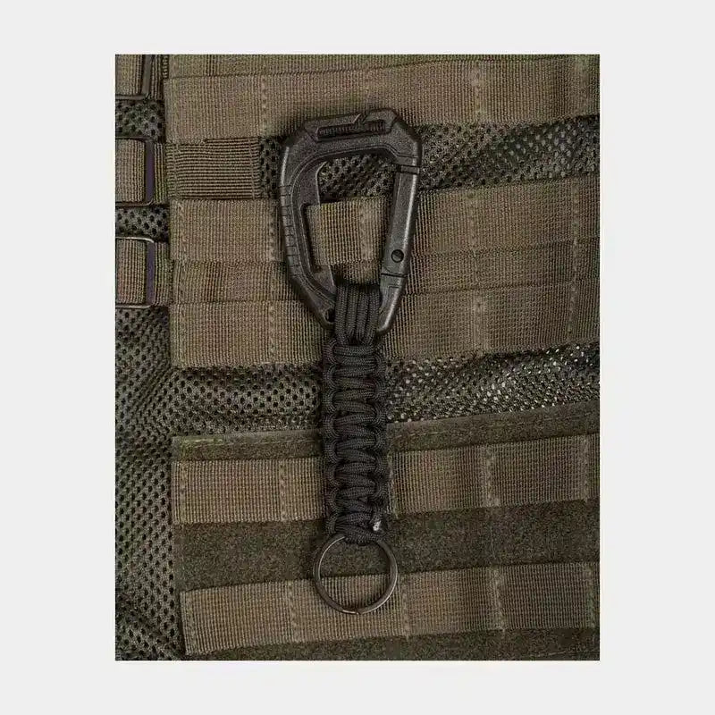 Llavero táctico de paracord negro sujeto mediante mosquetón al sistema MOLLE de un chaleco de equipamiento.