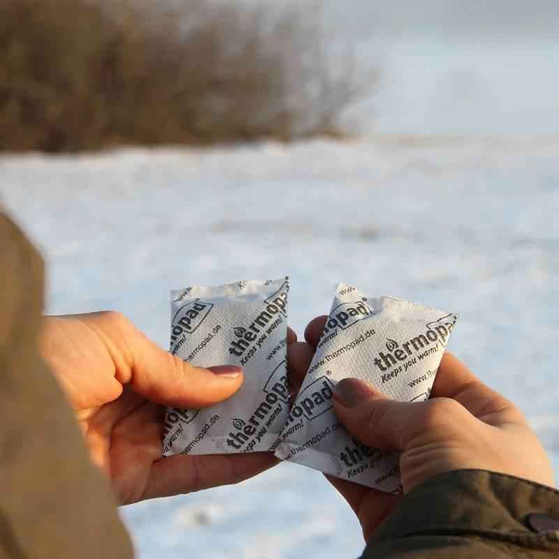 Par de calentadores de manos Thermopad envueltos en papel, en manos