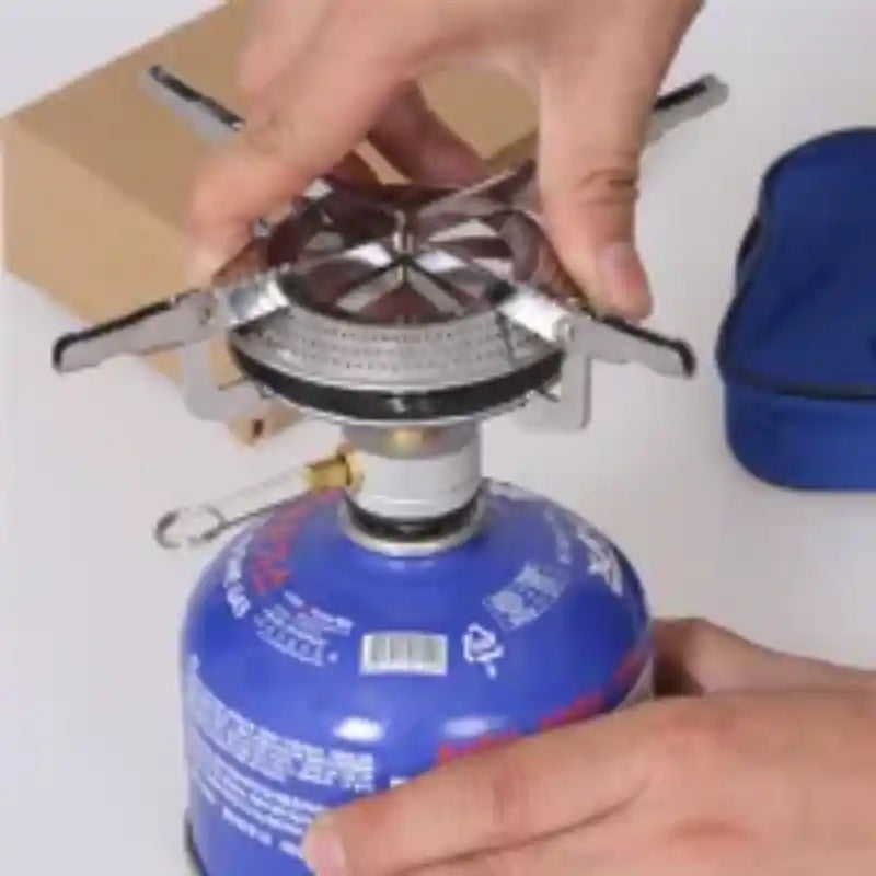 Hornillo de gas táctico con quemador circular y base sobre botella azul