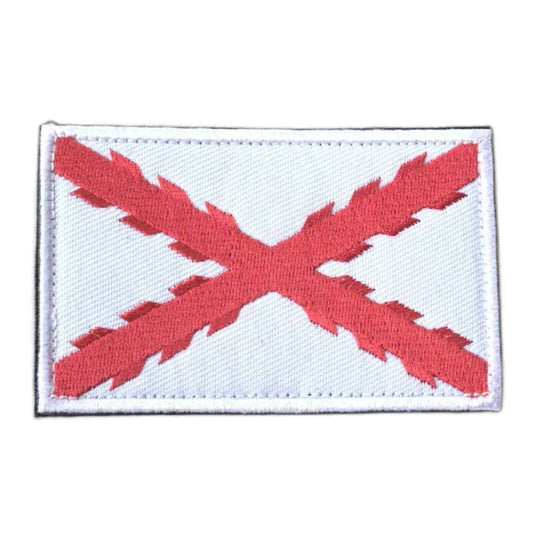 Parche rectangular de tela con bandera roja en aspa sobre fondo claro y borde blanco